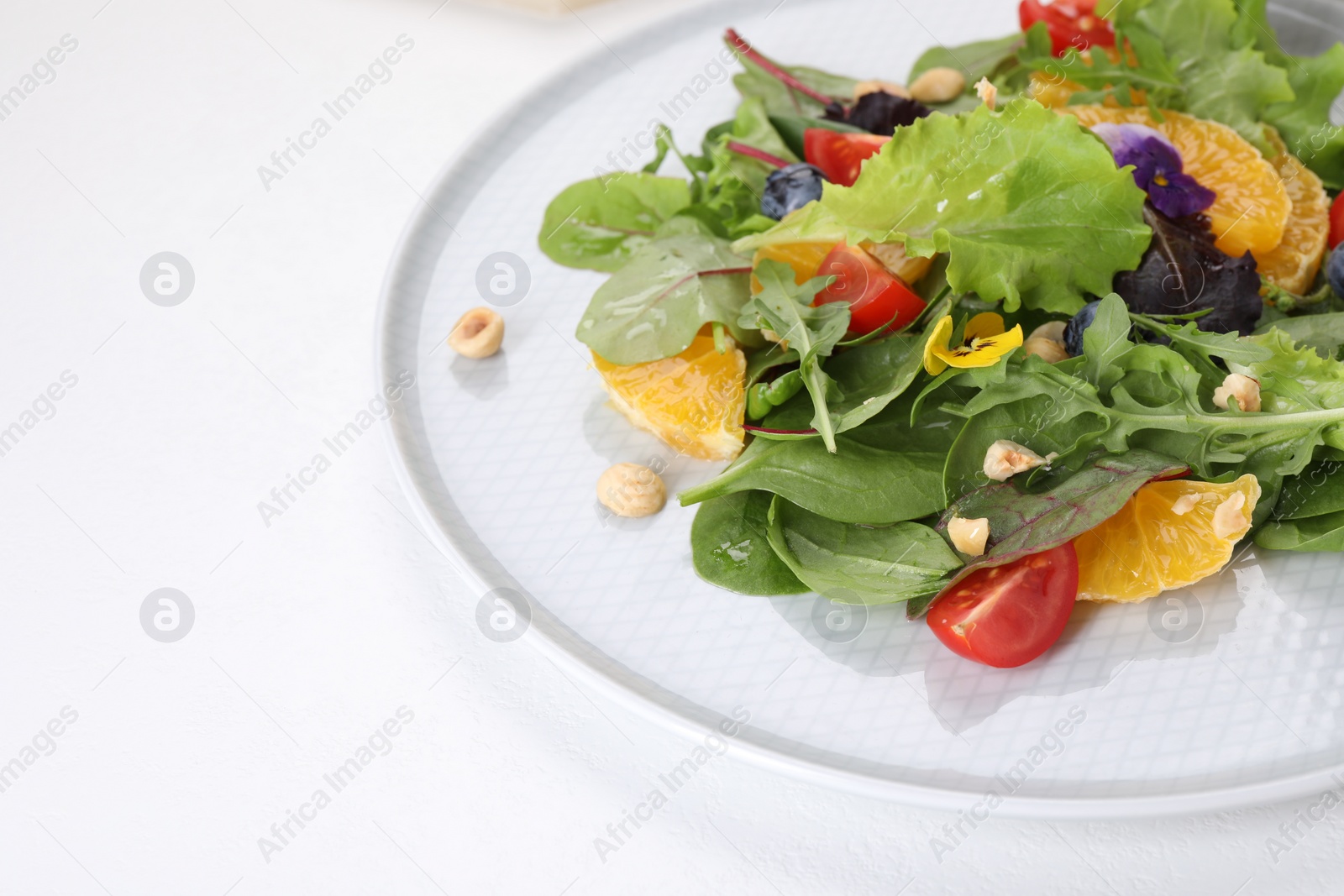 Photo of Delicious salad with tomatoes and orange slices on white table, space for text