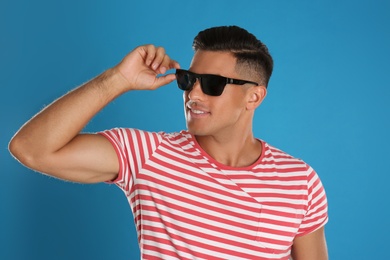 Photo of Handsome man wearing sunglasses on blue background