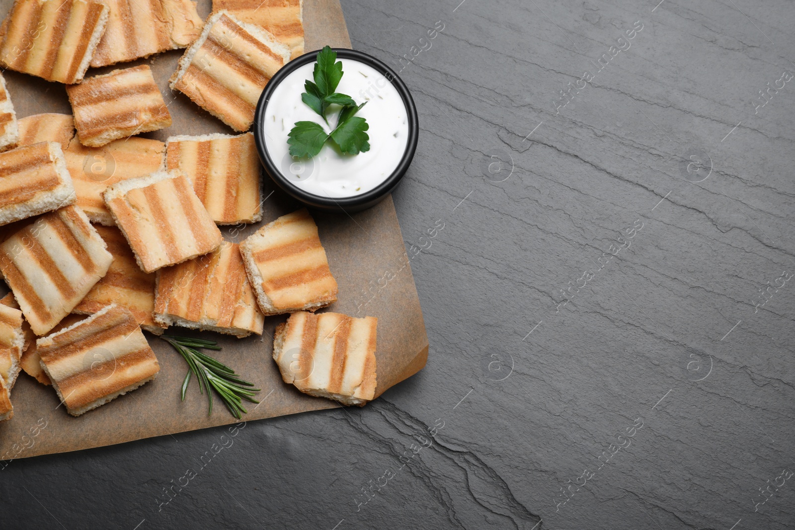 Photo of Delicious pita chips and sauce on black table, top view. Space for text