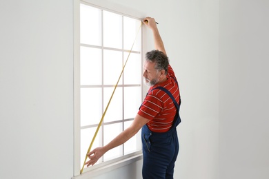 Service man measuring window for installation indoors. Space for text