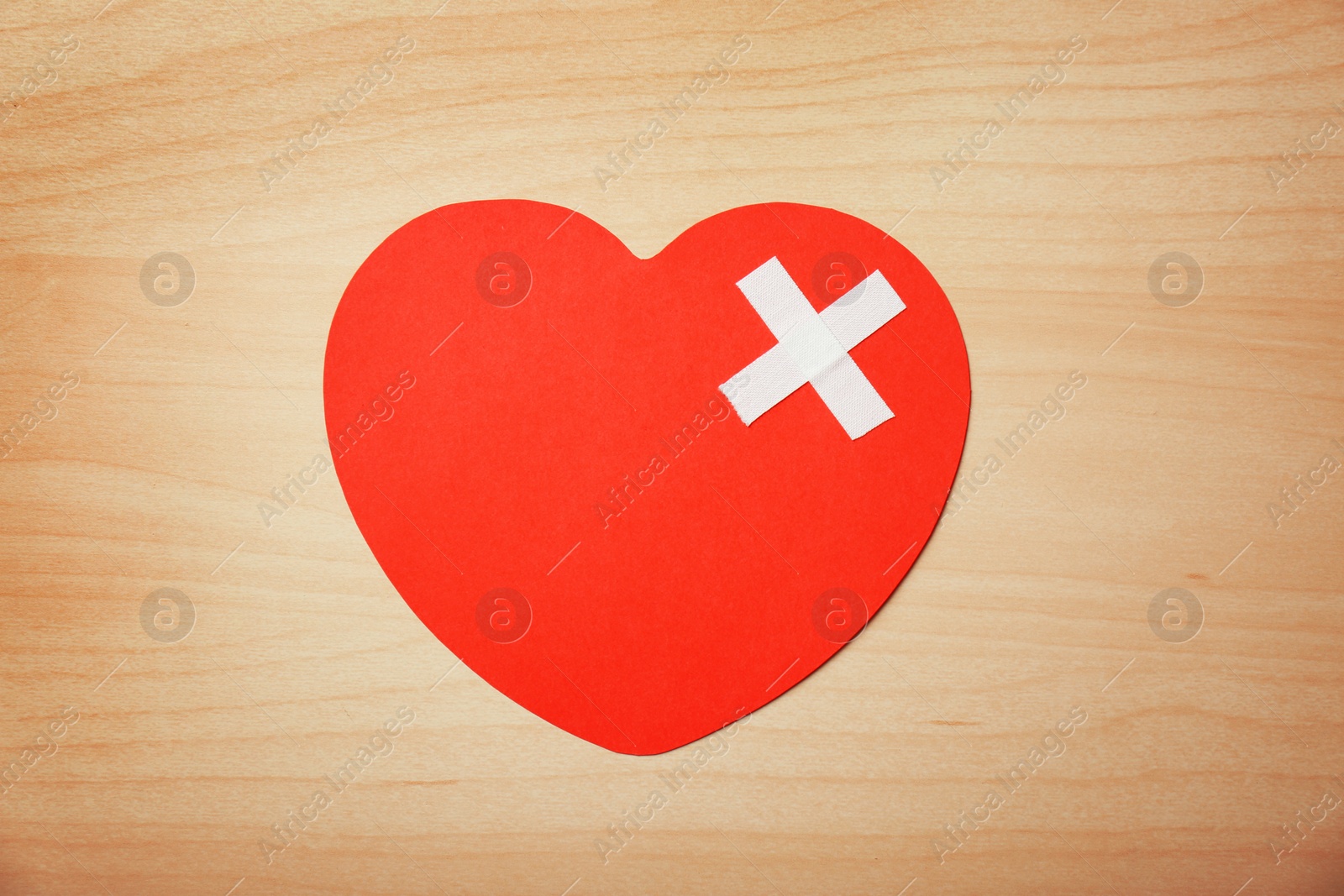 Photo of Paper heart with adhesive plasters on wooden background, top view. Relationship problems