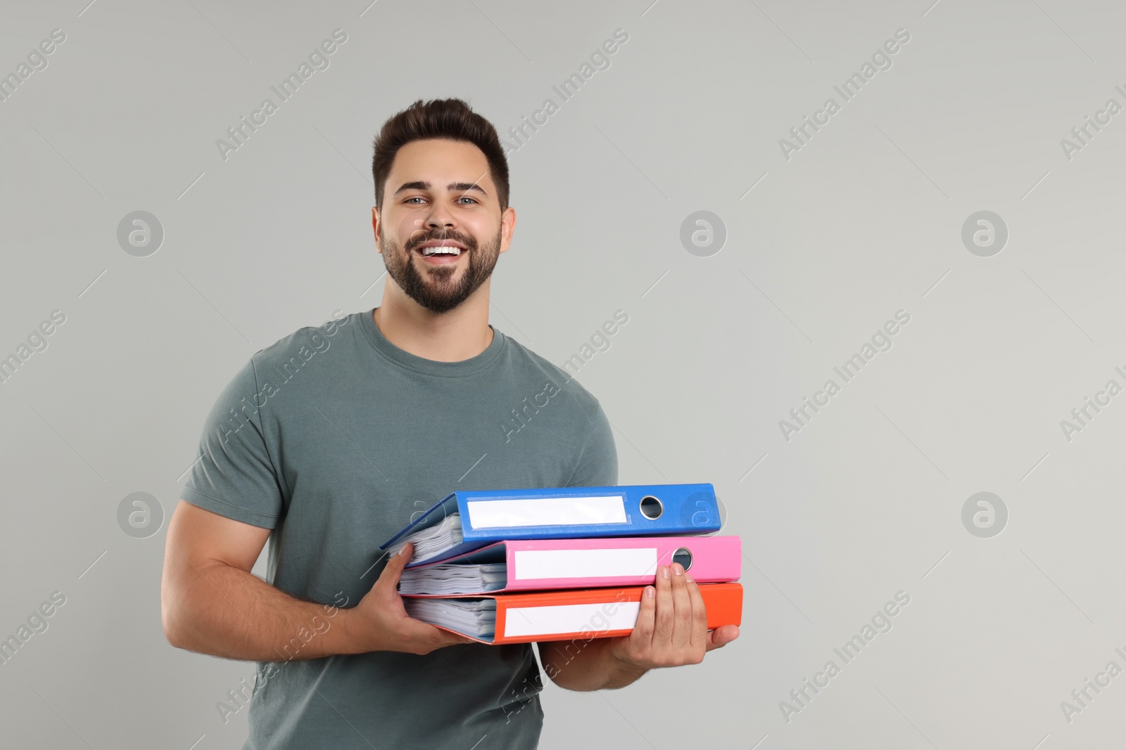 Photo of Happy man with folders on light gray background, space for text