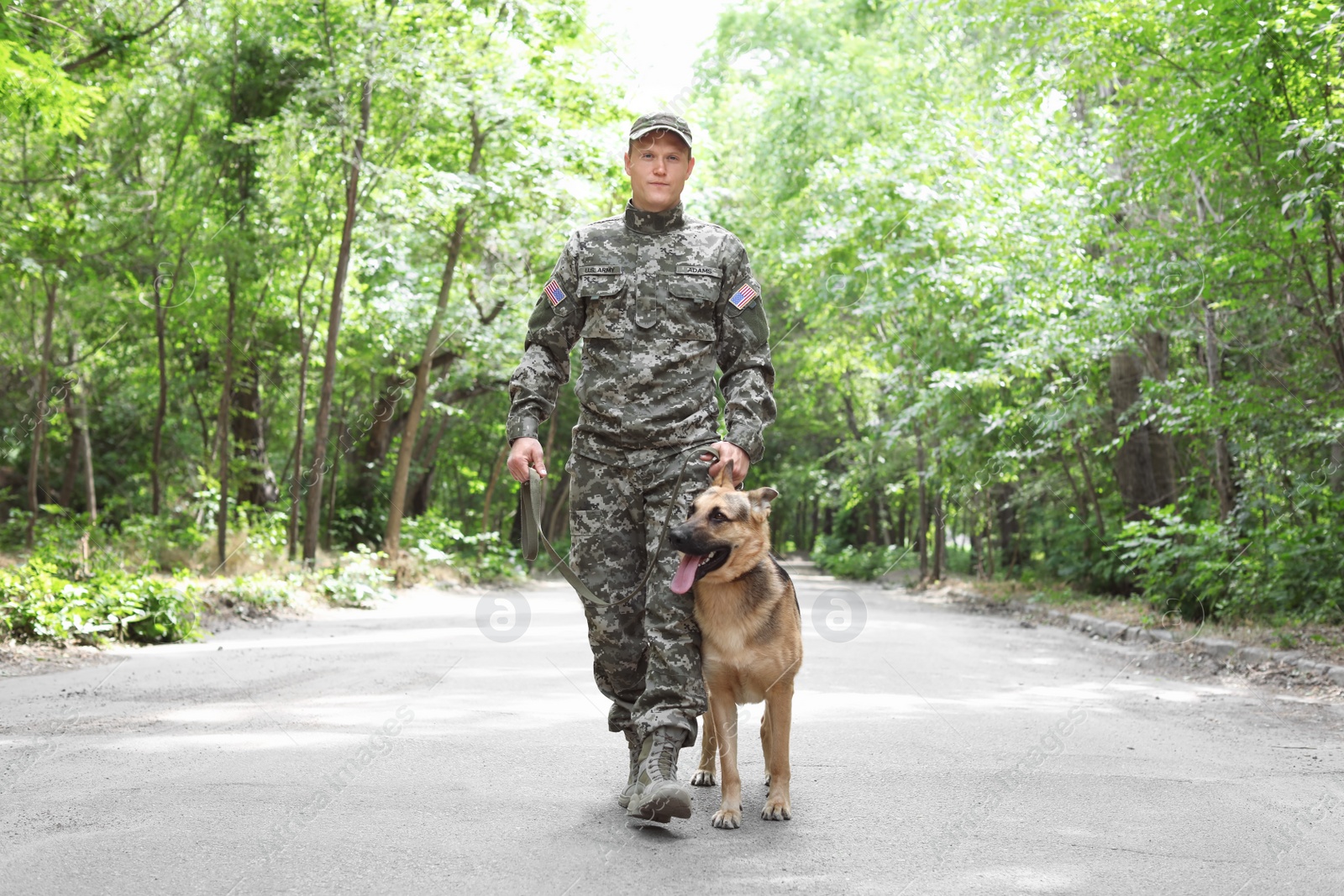 Photo of Man in military uniform with German shepherd dog, outdoors