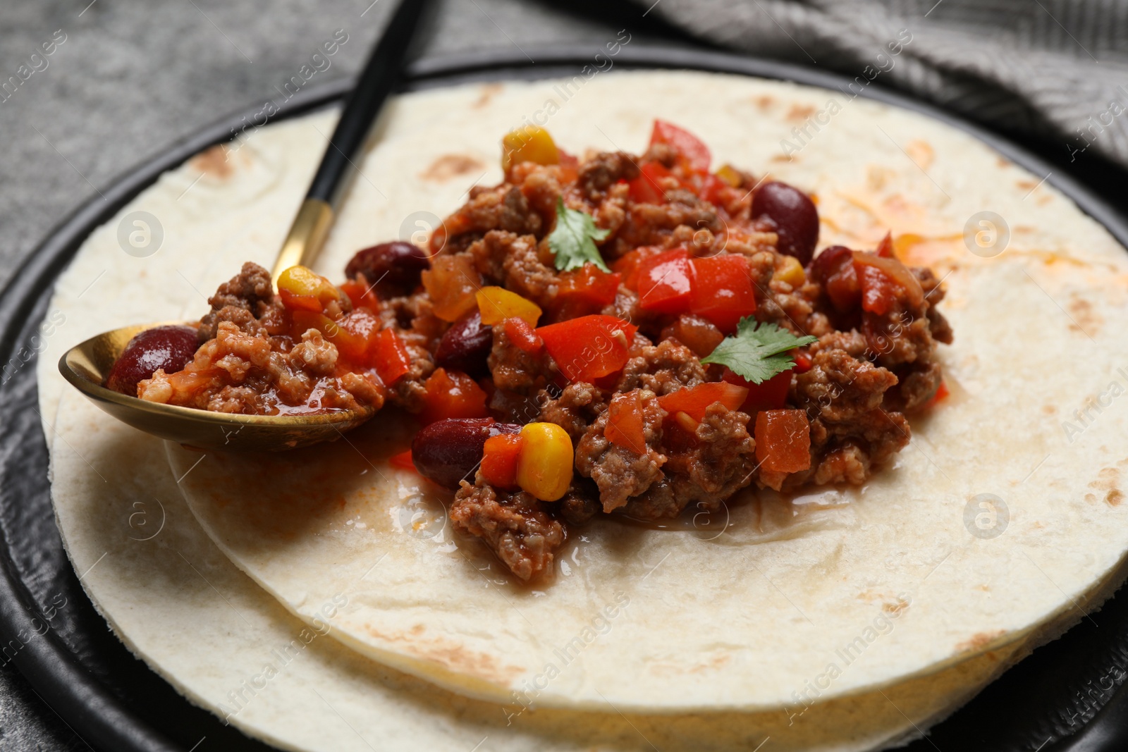 Photo of Tasty chili con carne with tortilla on grey table, closeup