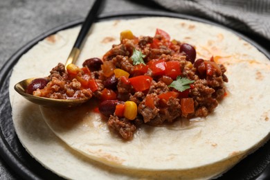 Photo of Tasty chili con carne with tortilla on grey table, closeup