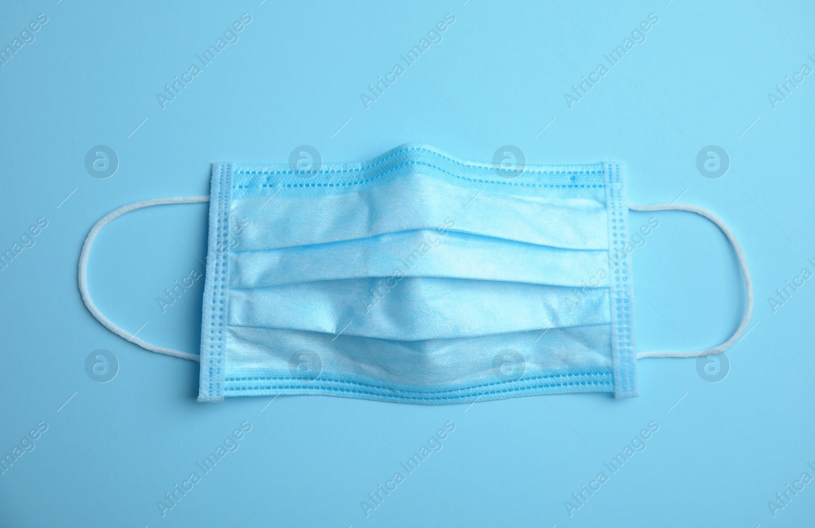 Photo of Medical face mask on blue background, top view