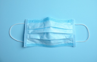 Photo of Medical face mask on blue background, top view