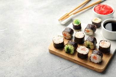 Photo of Tasty sushi rolls served on grey table. Space for text
