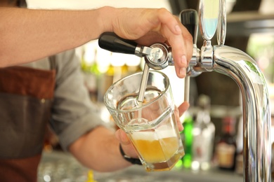 Photo of Bartender pouring fresh cold beer from tap, closeup