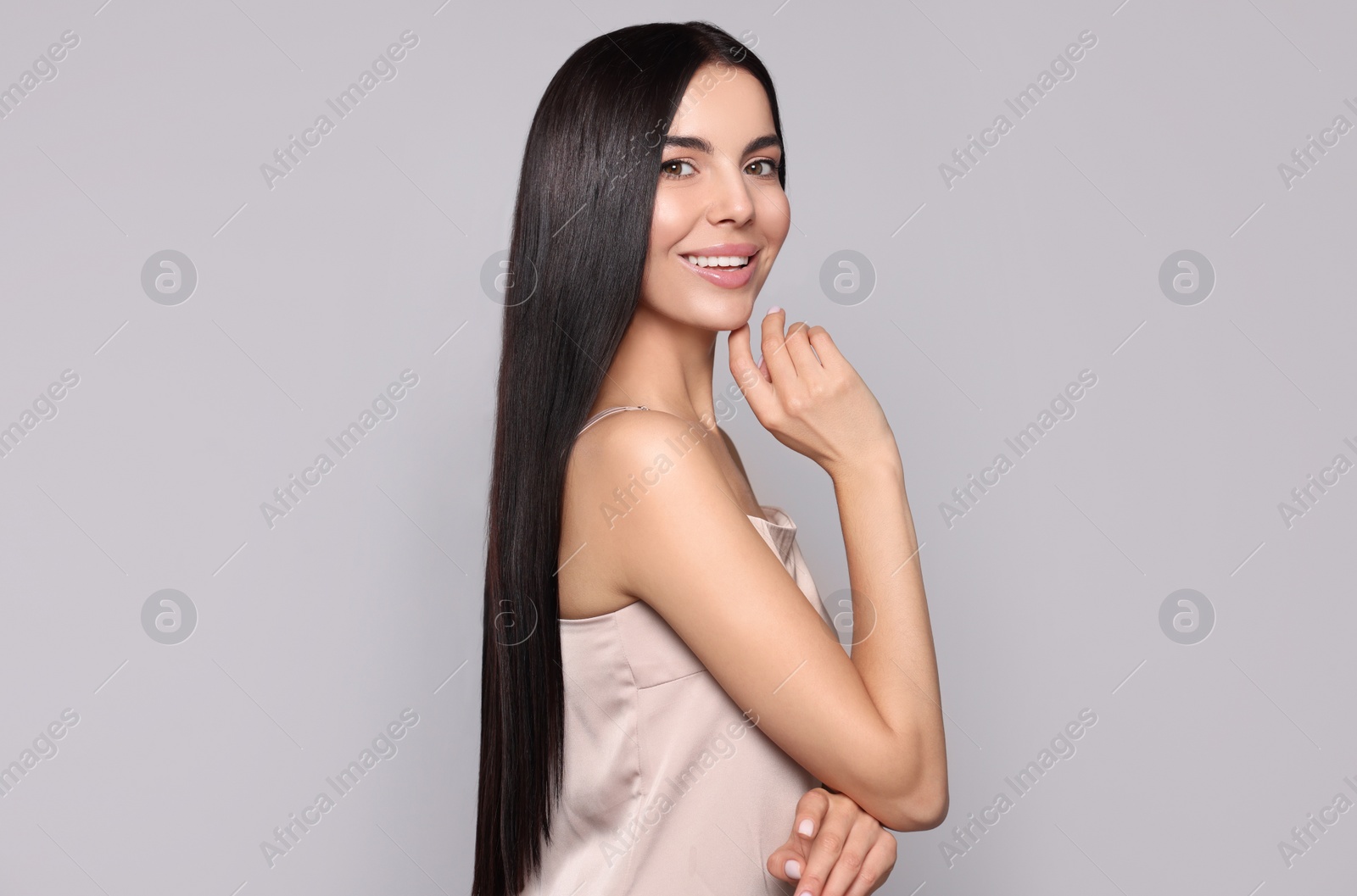 Photo of Portrait of beautiful young woman with healthy strong hair on light grey background