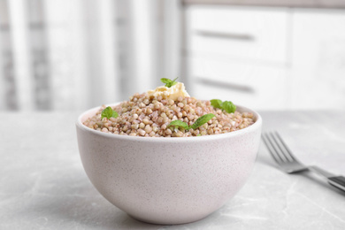 Photo of Tasty buckwheat porridge with butter on grey marble table indoors