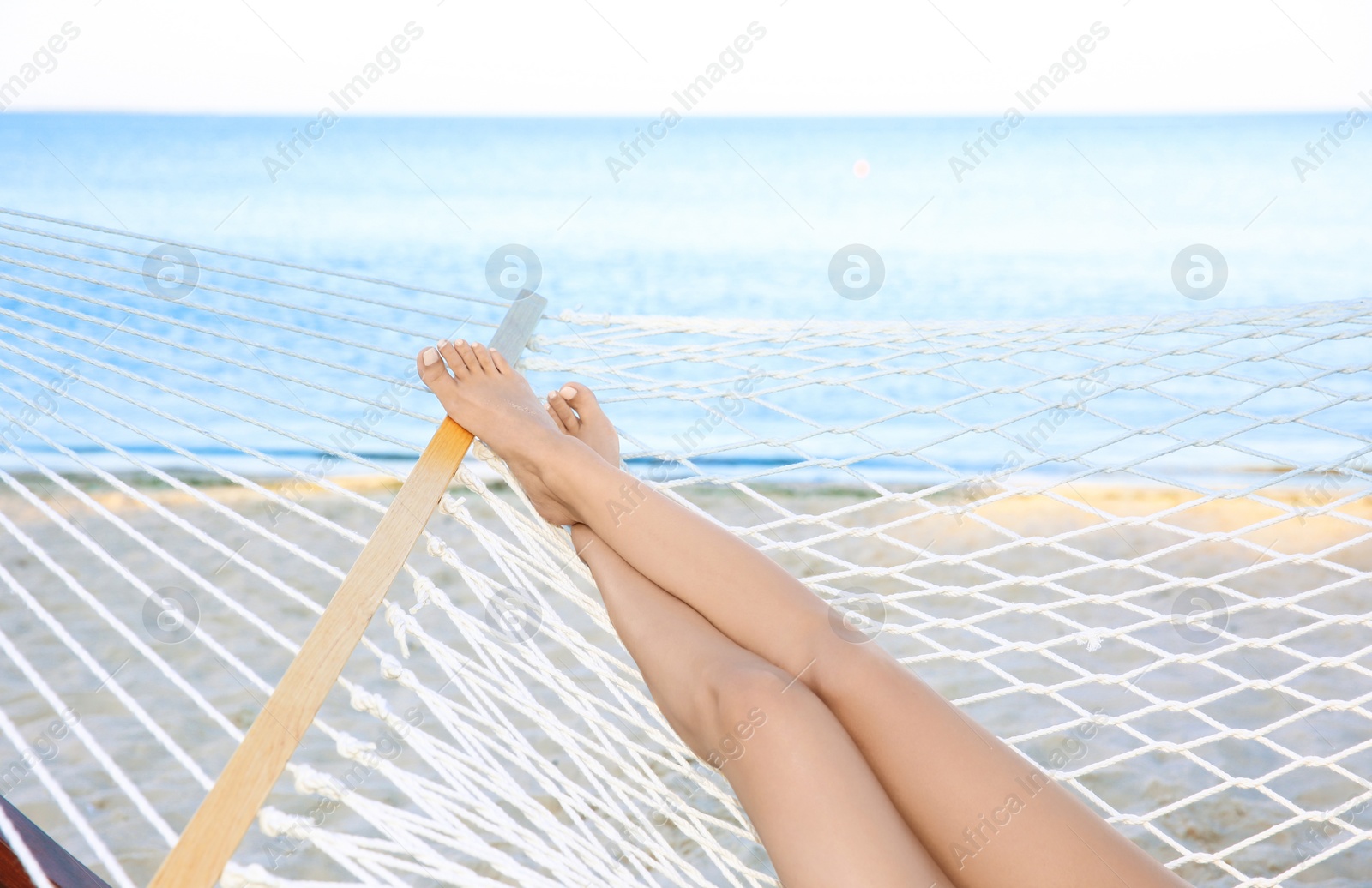 Photo of Young woman resting in hammock at seaside. Summer vacation