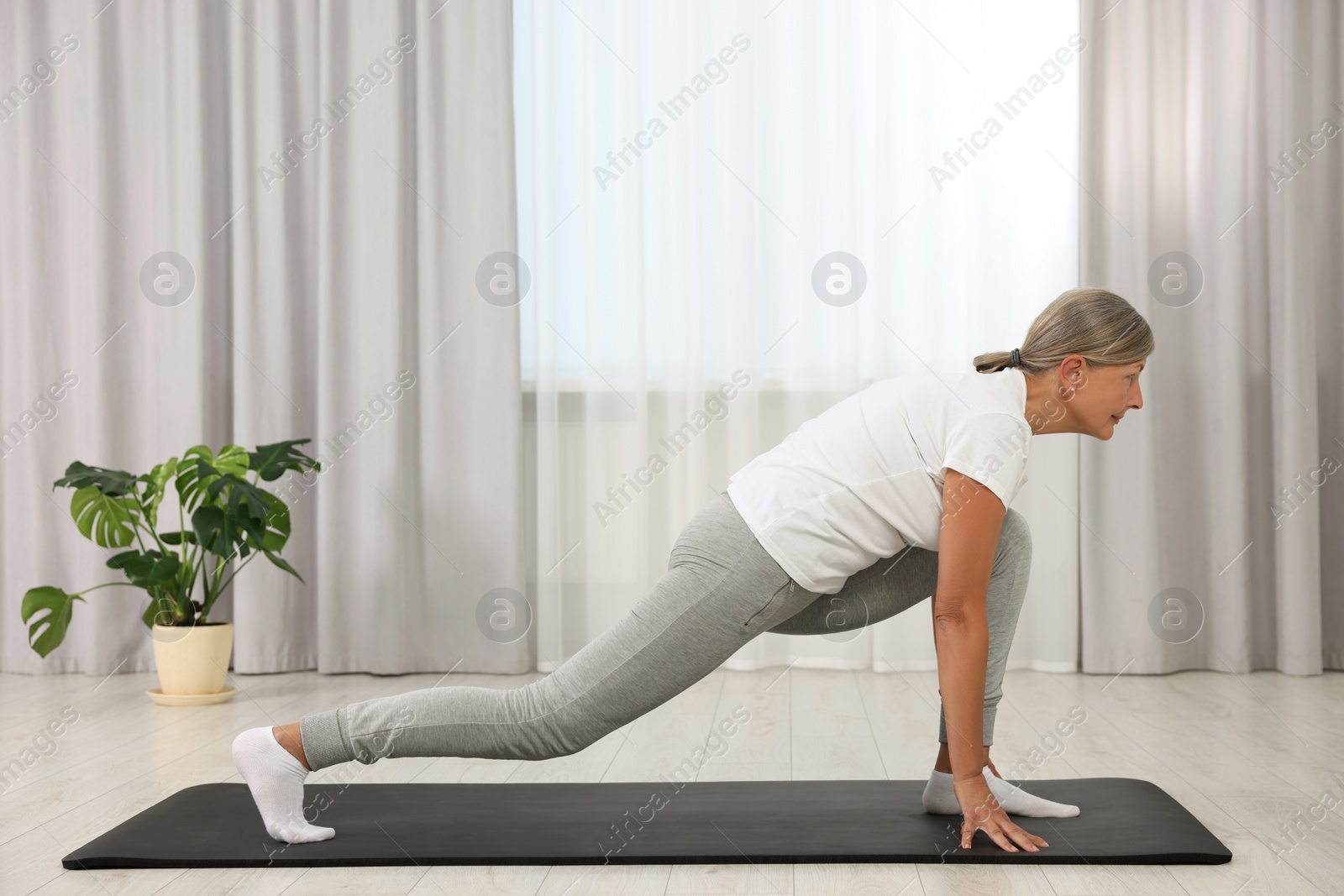 Photo of Senior woman practicing yoga on mat at home