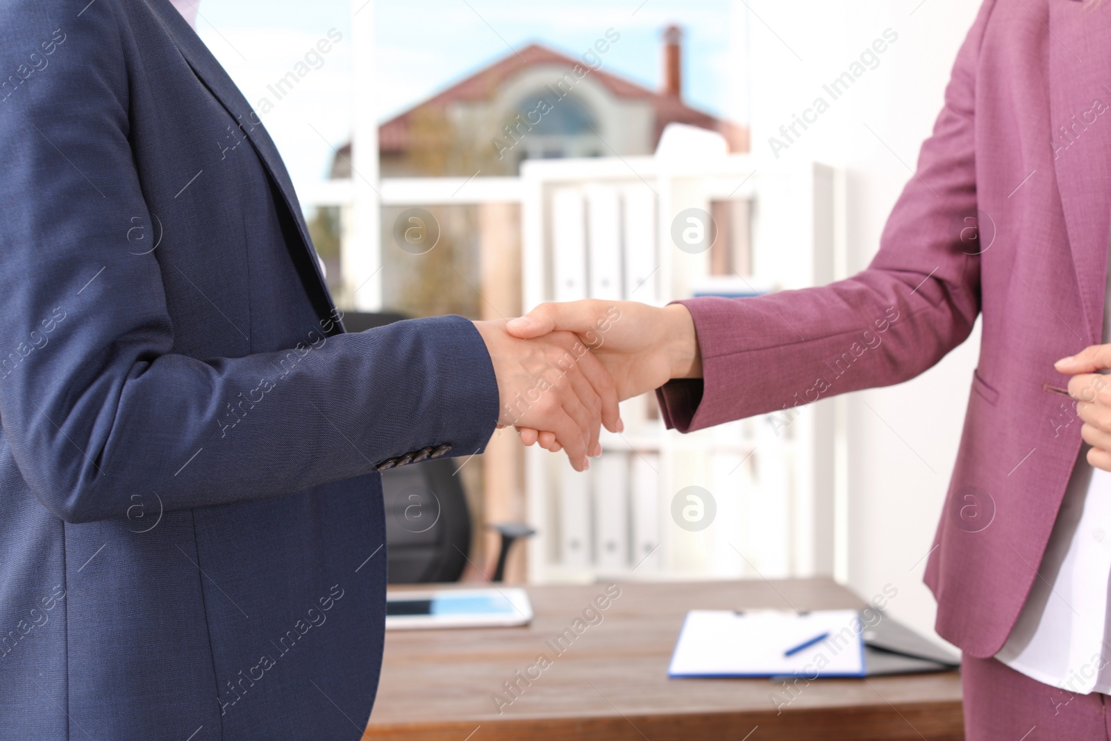 Photo of Human resources manager shaking hands with applicant during job interview in office