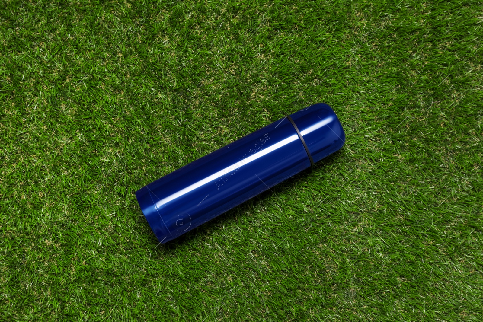 Photo of Modern blue thermos on green grass, top view