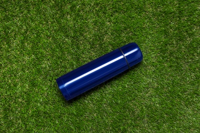 Modern blue thermos on green grass, top view