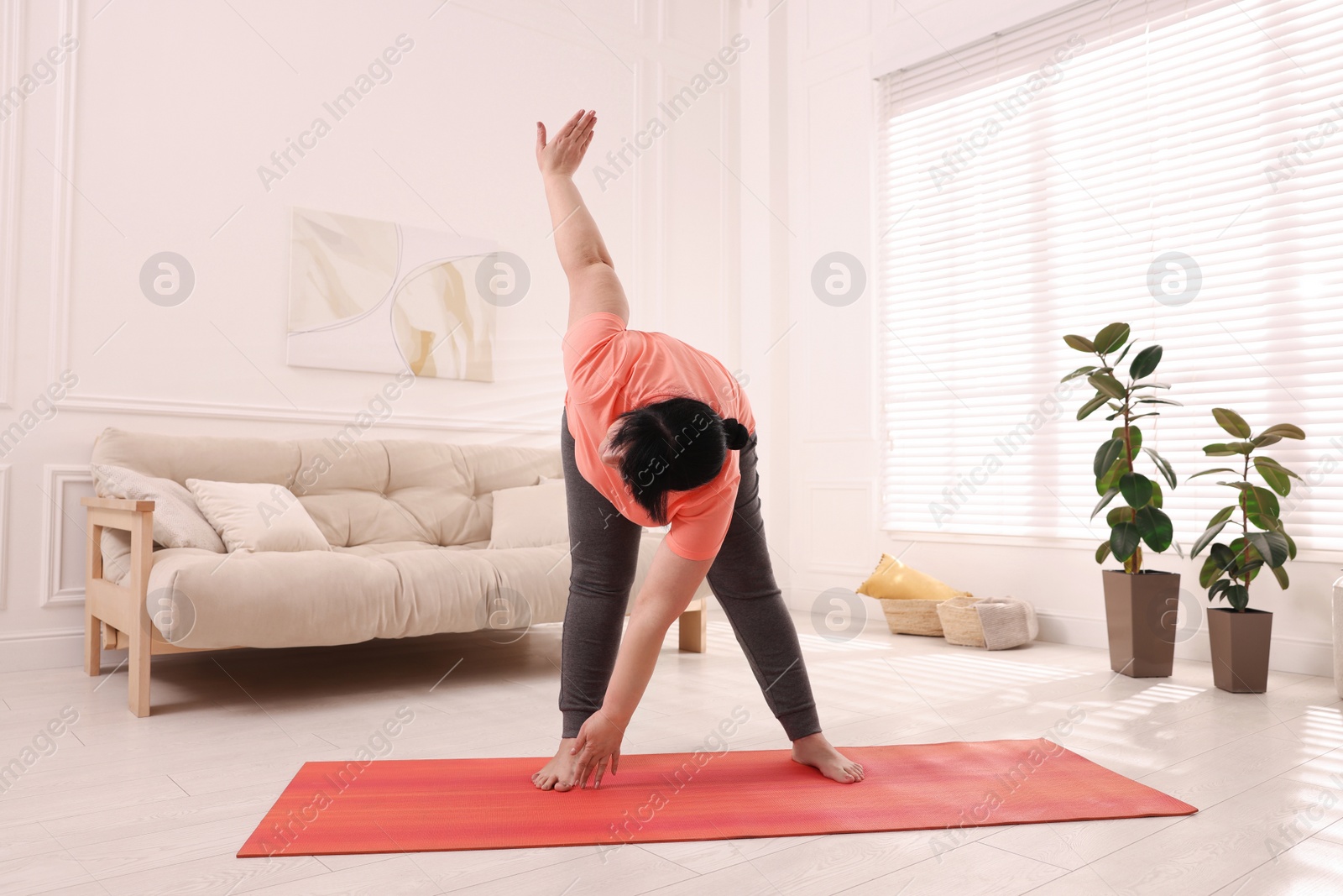 Photo of Overweight mature woman doing exercise on yoga mat at home