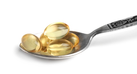 Photo of Spoon with cod liver oil pills on white background