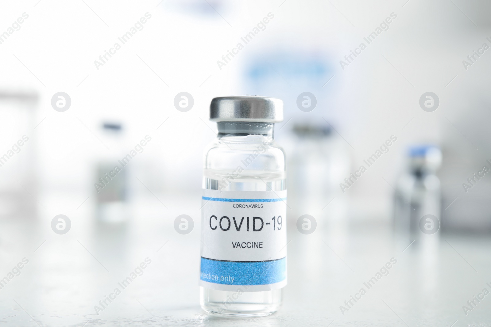 Photo of Vial with vaccine against Covid-19 on white table indoors