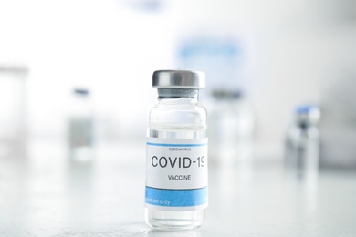 Photo of Vial with vaccine against Covid-19 on white table indoors