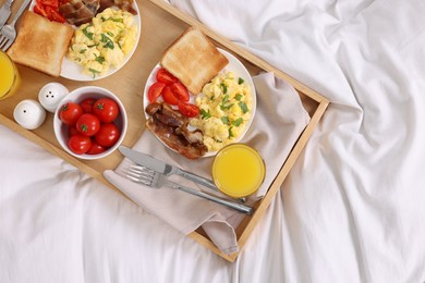 Photo of Good morning. Tray with tasty breakfast on bed, top view