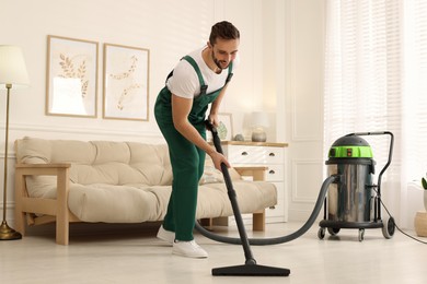 Photo of Professional janitor vacuuming floor in living room