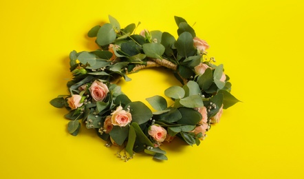 Photo of Wreath made of beautiful flowers on yellow background