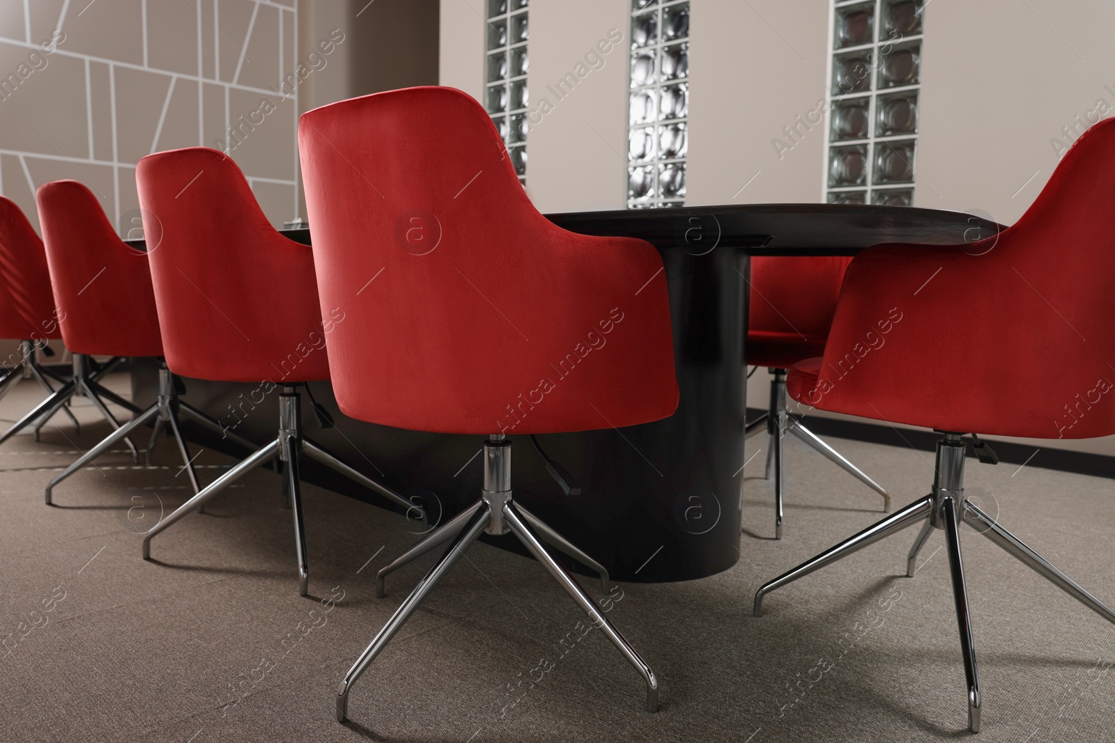 Photo of Stylish red office chairs and large table in empty conference room