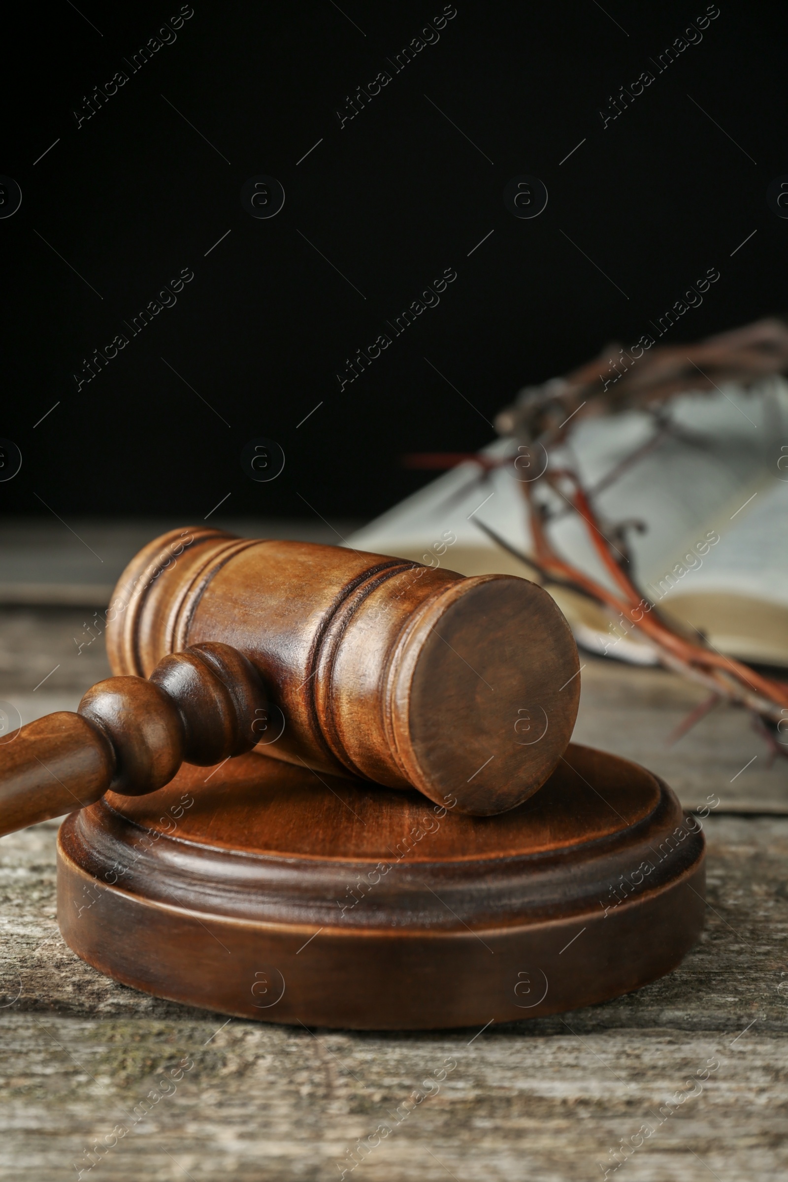 Photo of Judge gavel on old wooden table against black background, closeup