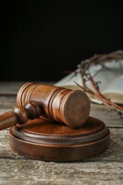 Photo of Judge gavel on old wooden table against black background, closeup