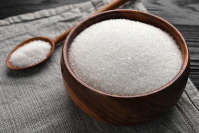 Photo of Granulated sugar in bowl and spoon on towel, closeup