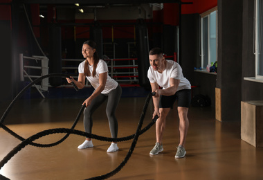 Photo of Couple working out with battle ropes in gym