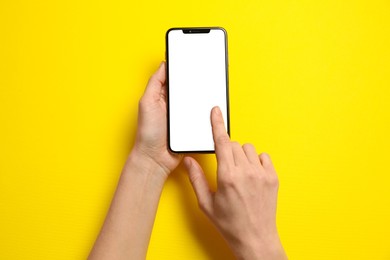 Photo of Woman using smartphone on yellow background, top view