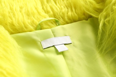 Photo of Blank clothing label on light green jacket, closeup