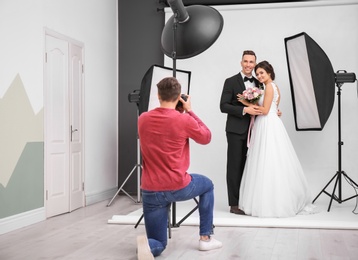 Photo of Professional photographer taking photo of wedding couple in studio