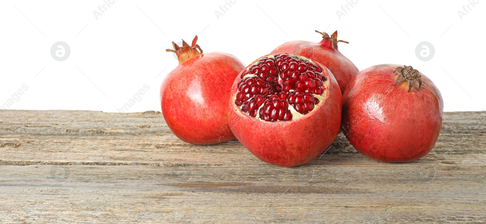 Photo of Fresh pomegranates on wooden table against white background, space for text