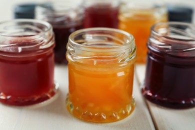 Photo of Jars of different jams on white table, closeup