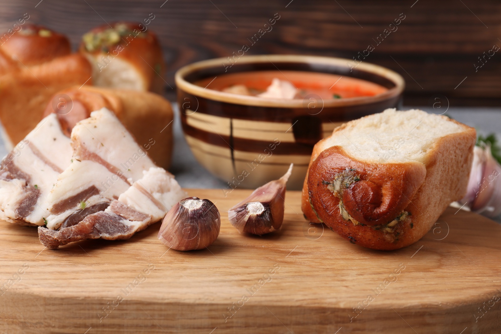 Photo of Delicious pampushky (buns with garlic) and salo served for borsch on table, closeup. Traditional Ukrainian cuisine