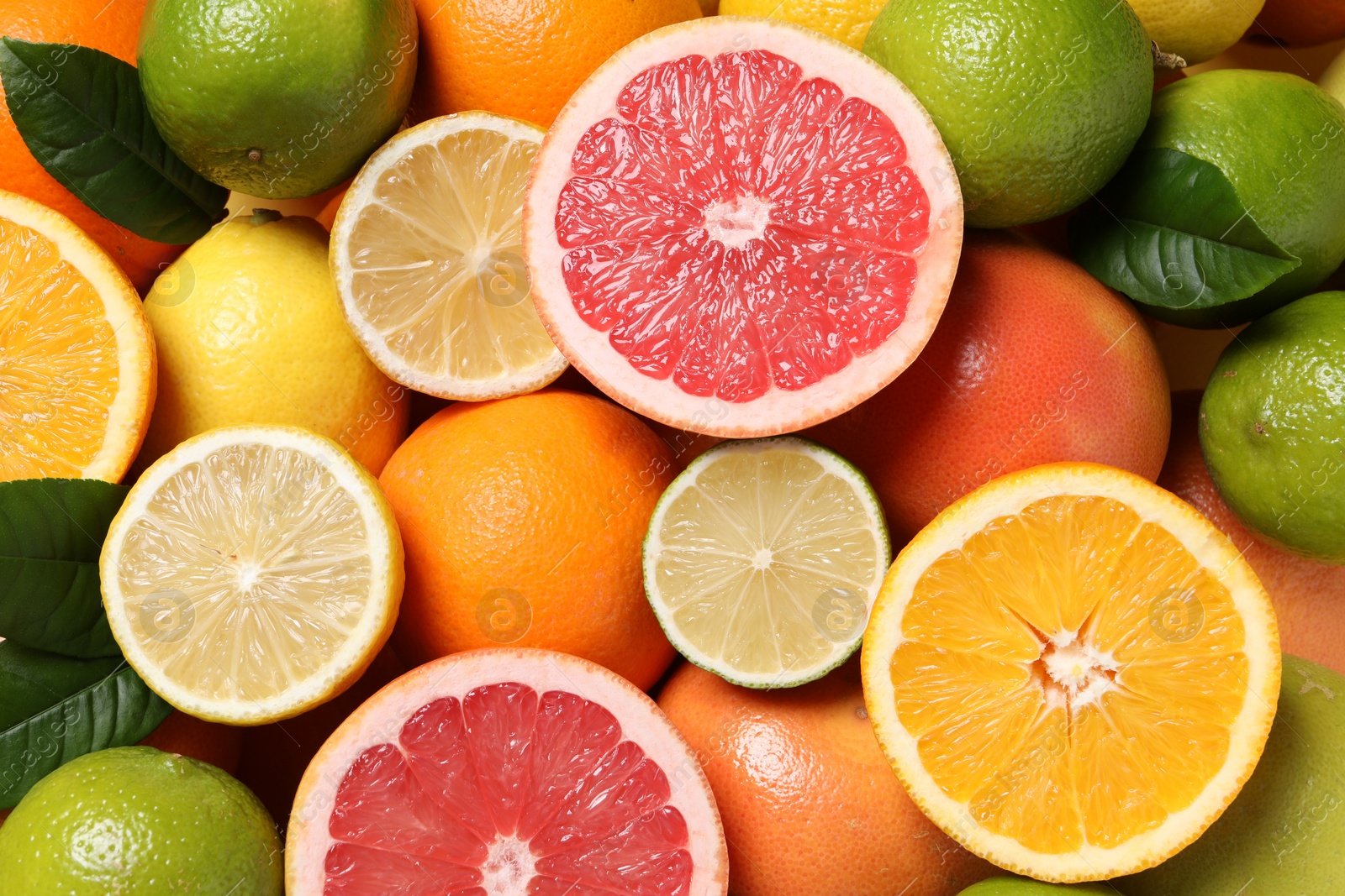 Photo of Different fresh citrus fruits and leaves as background, top view