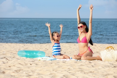 Photo of Happy mother and daughter on sandy beach near sea. Summer holidays with family