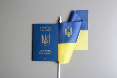 Photo of Ukrainian travel passport and national flag on grey background, top view. International relationships