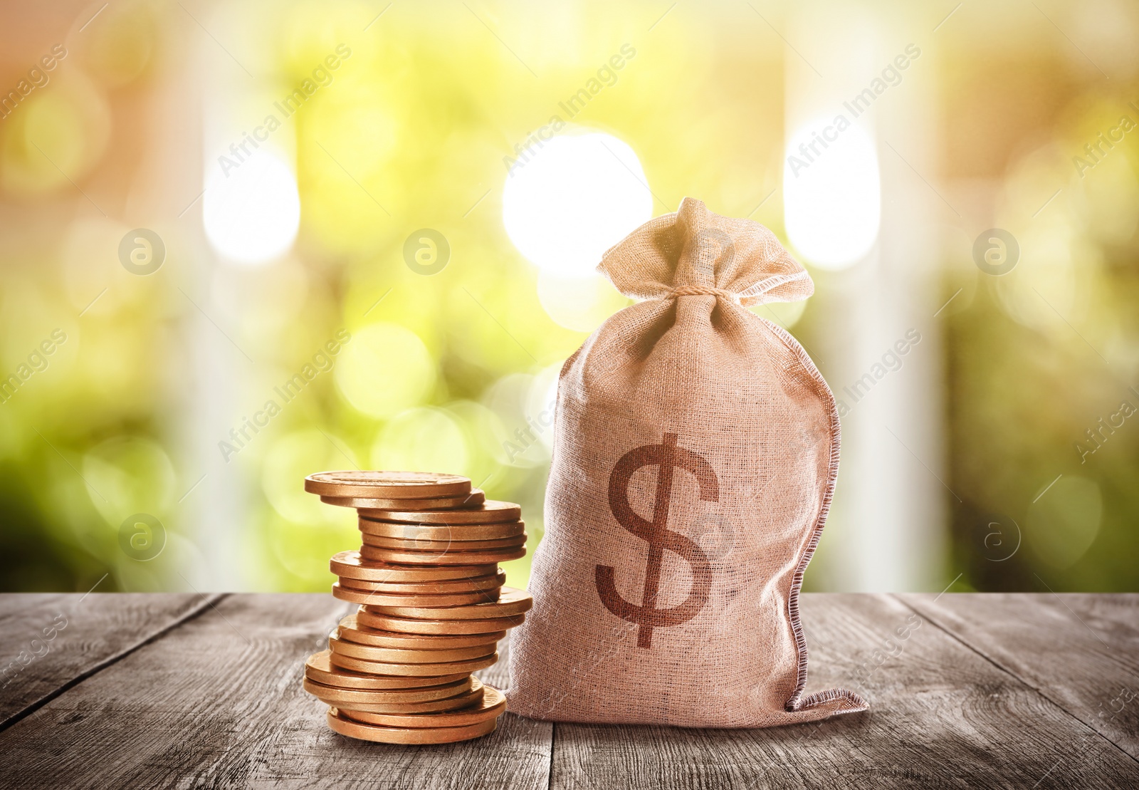 Image of Burlap bag with dollar sign and coins on wooden table indoors