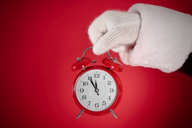 Photo of Santa Claus holding alarm clock on red background, closeup. Christmas countdown