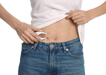 Photo of Young woman measuring body fat with caliper on white background, closeup