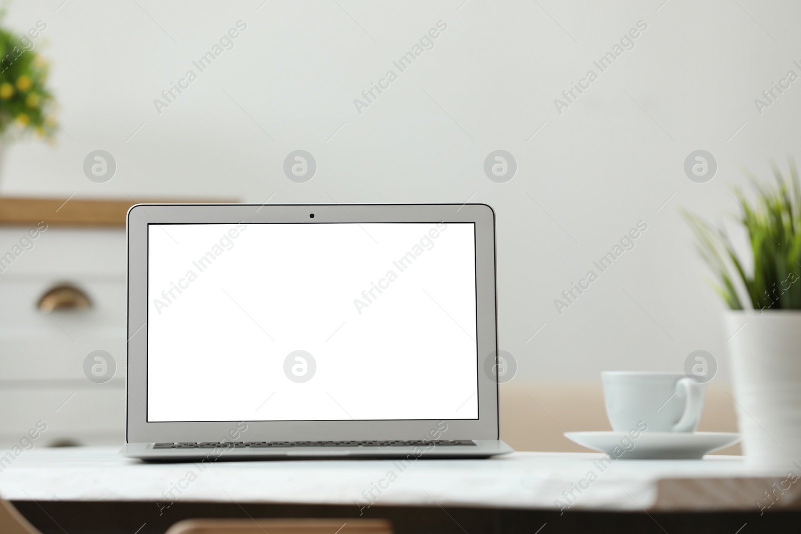 Photo of Laptop with blank screen on table indoors. Space for text