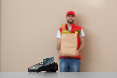 Photo of Bank terminal and blurred delivery man with food on background. Space for text