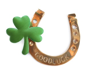 Golden horseshoe and decorative clover leaf on white background, top view. Saint Patrick's Day celebration