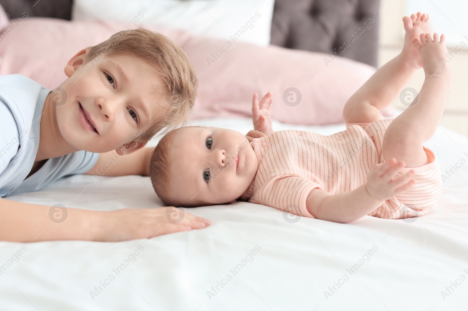 Photo of Cute little baby with elder brother lying on bed at home