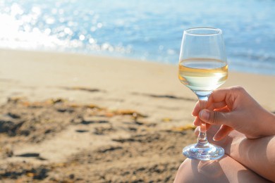 Photo of Woman with glass of tasty wine near sea, closeup. Space for text