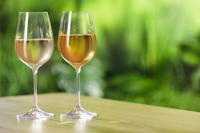 Photo of Tasty white wine in glasses on wooden table, space for text